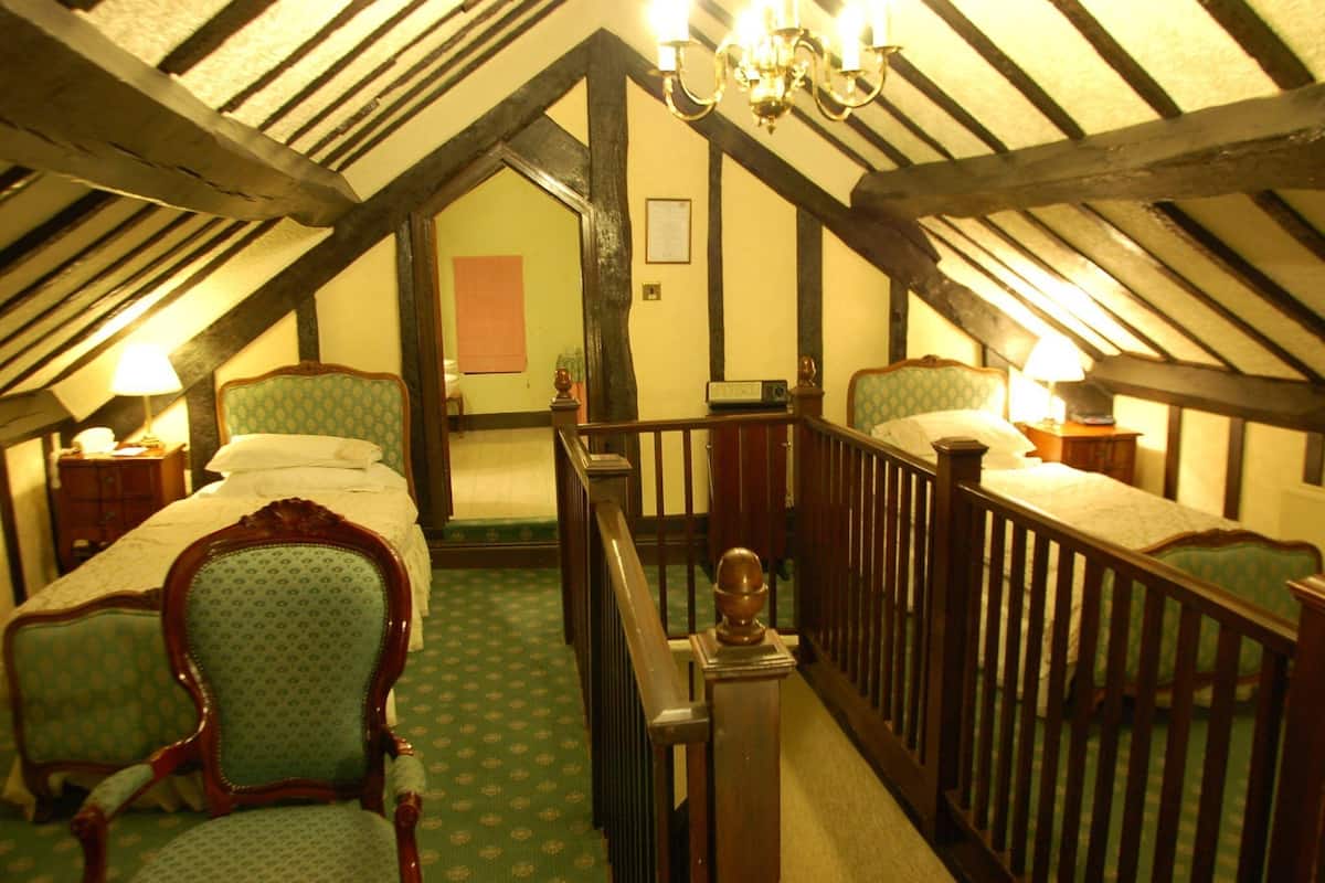 A room with two beds, a chandelier, and a staircase.