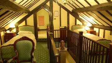 A room with two beds, a chandelier, and a staircase.