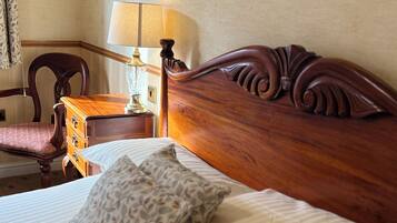 A neatly made bed with a wooden headboard, a patterned pillow, and a bedside table with a lamp.