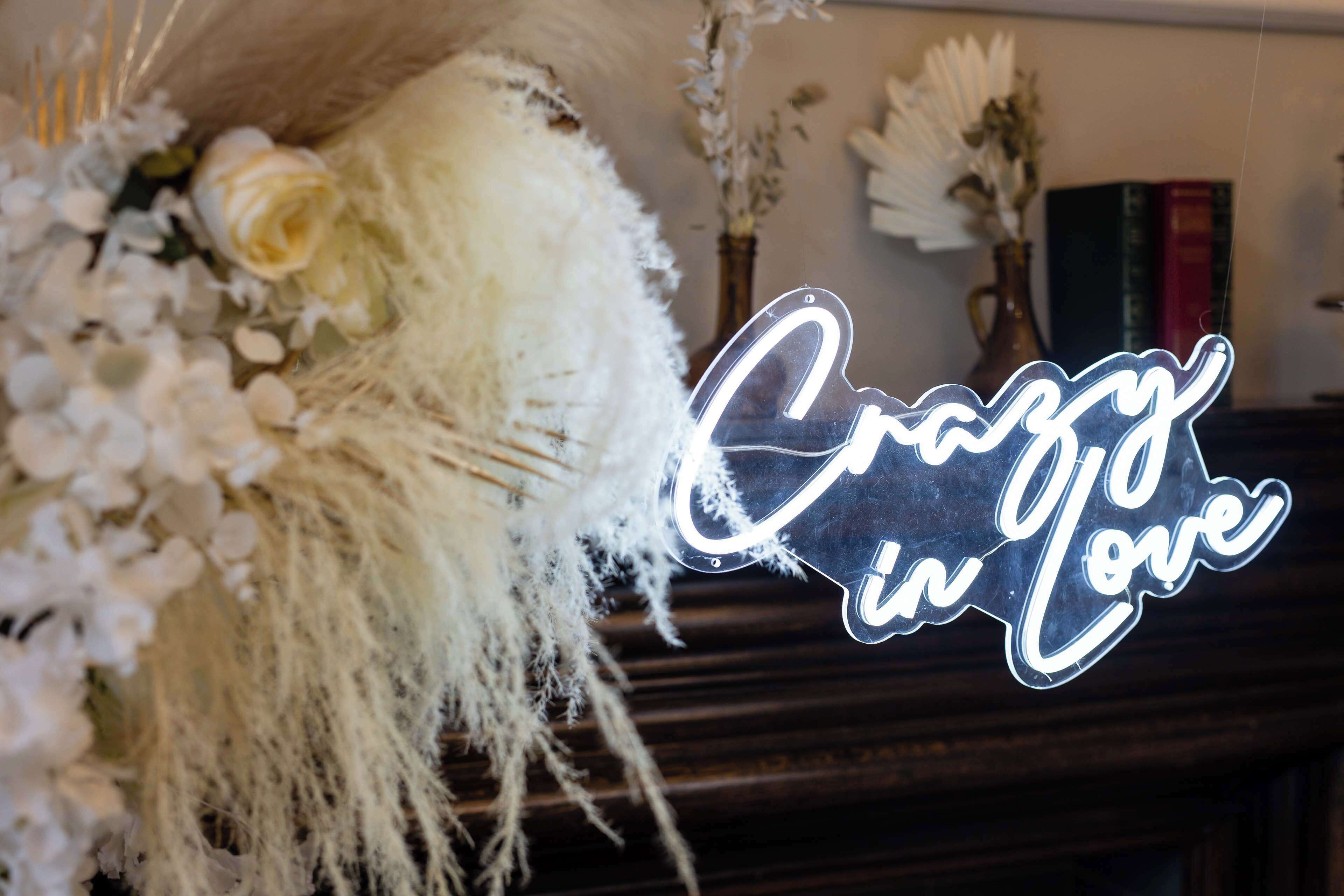 A neon sign with the text "Crazy in Love" in a cursive font, placed on a dark wooden surface.