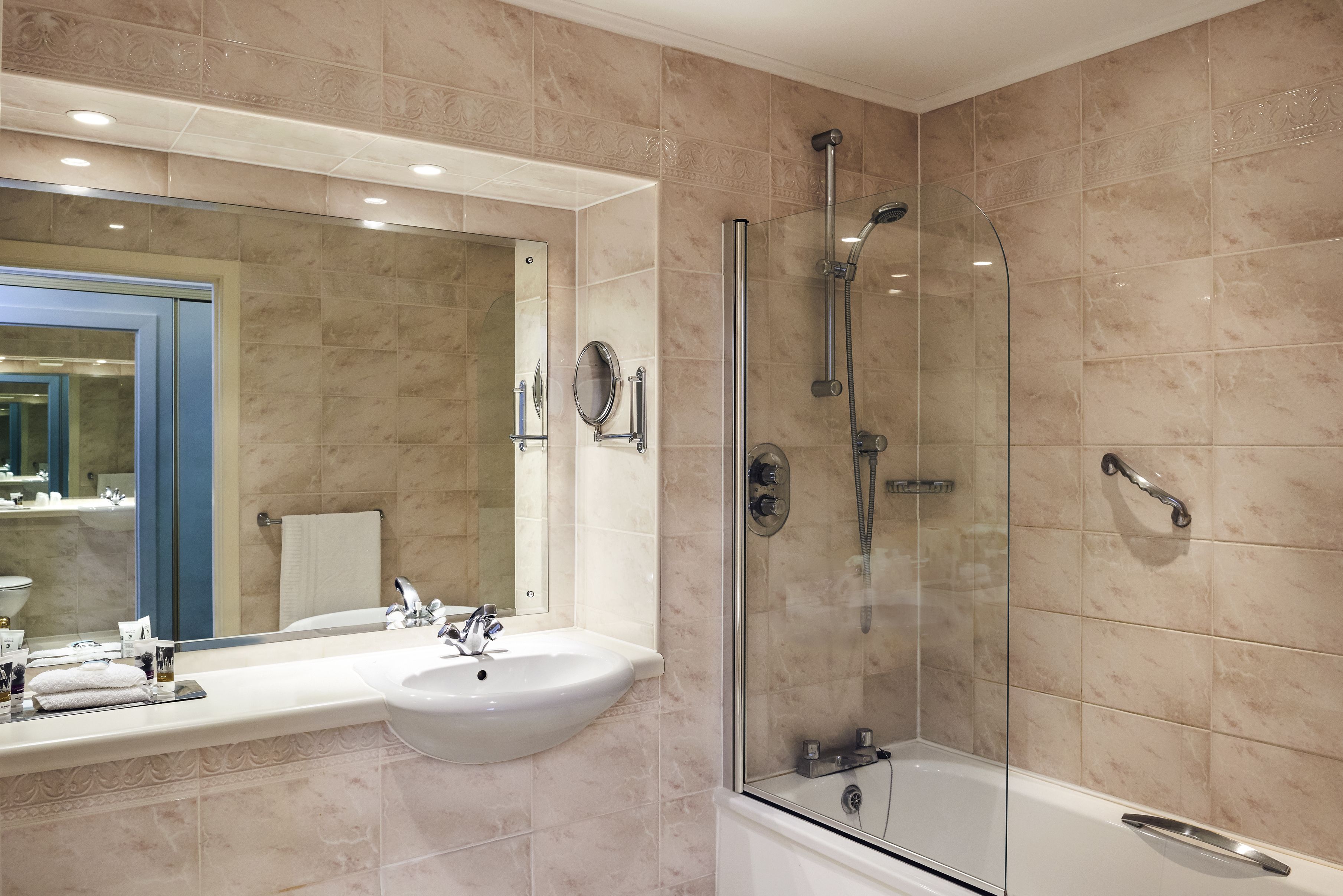 A modern bathroom with a glass-enclosed shower, a sink, and a large mirror.