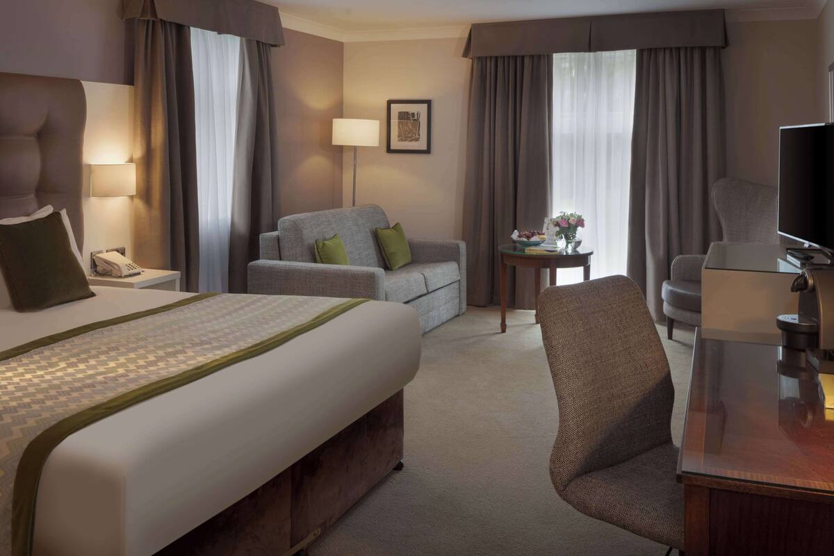 Une chambre d’hôtel avec un grand lit, un canapé, un bureau avec une lampe et un téléviseur.