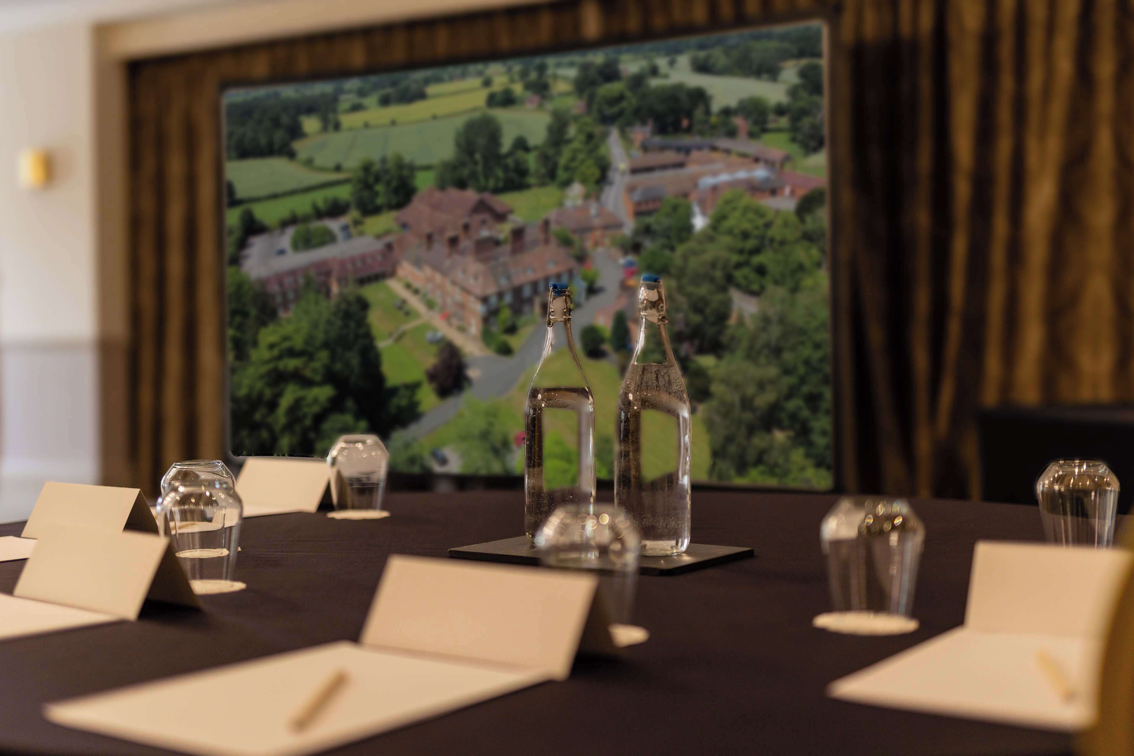 A conference table with name cards, water glasses, and a large framed map in the background.