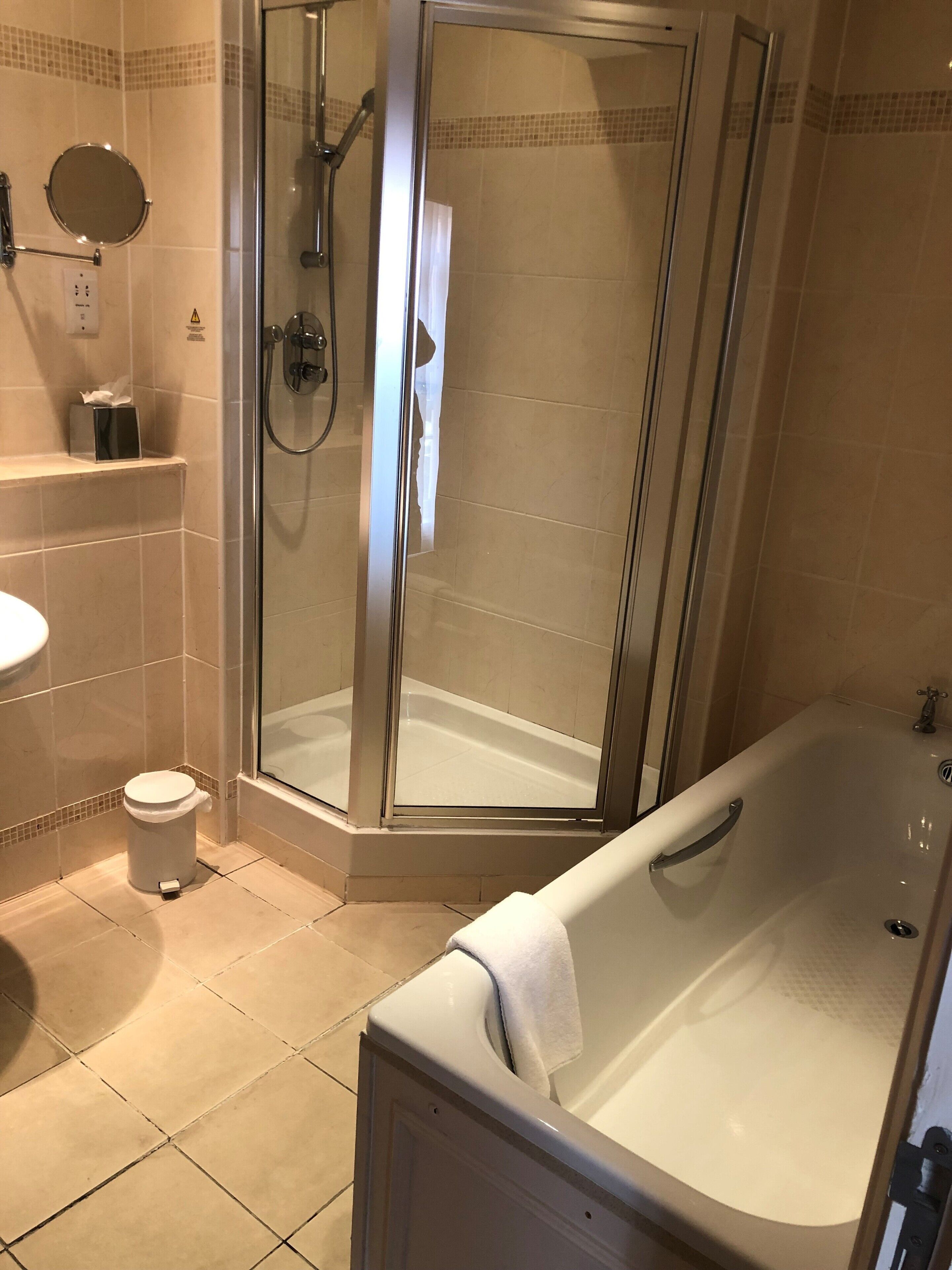 Un baño moderno con ducha de vidrio, bañera, inodoro y lavamanos.