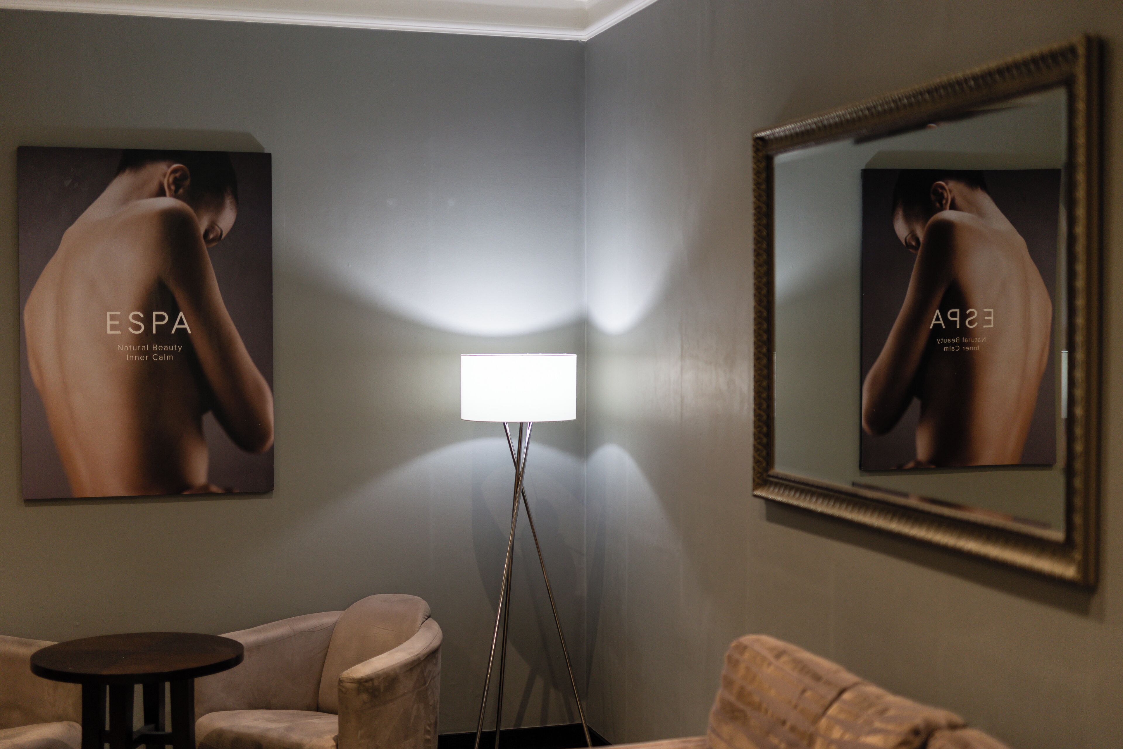 A room with a sofa, a small round table, a floor lamp, and two posters on the wall.