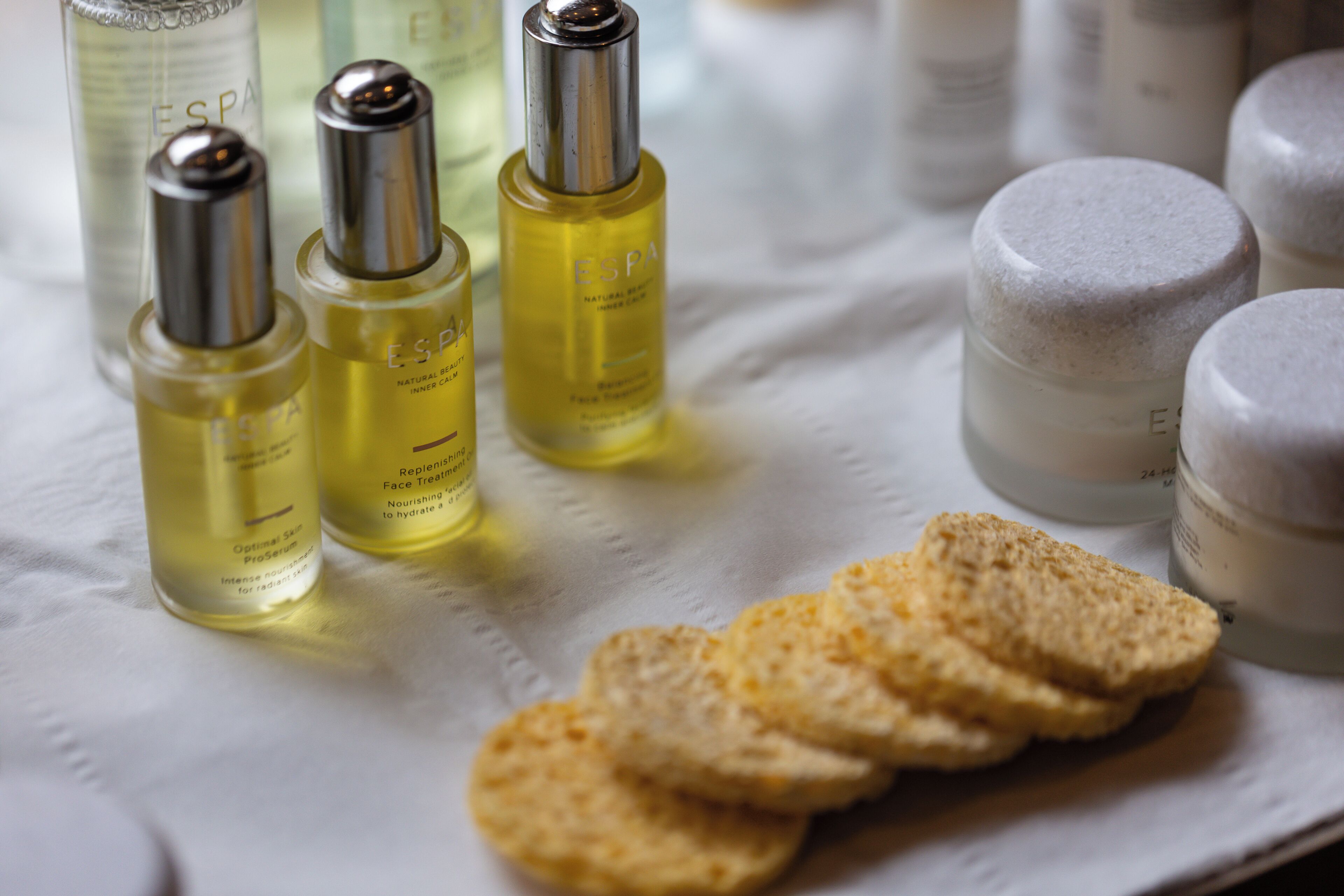 Bottles of ESPA face treatment and cream, along with some biscuits on a table.