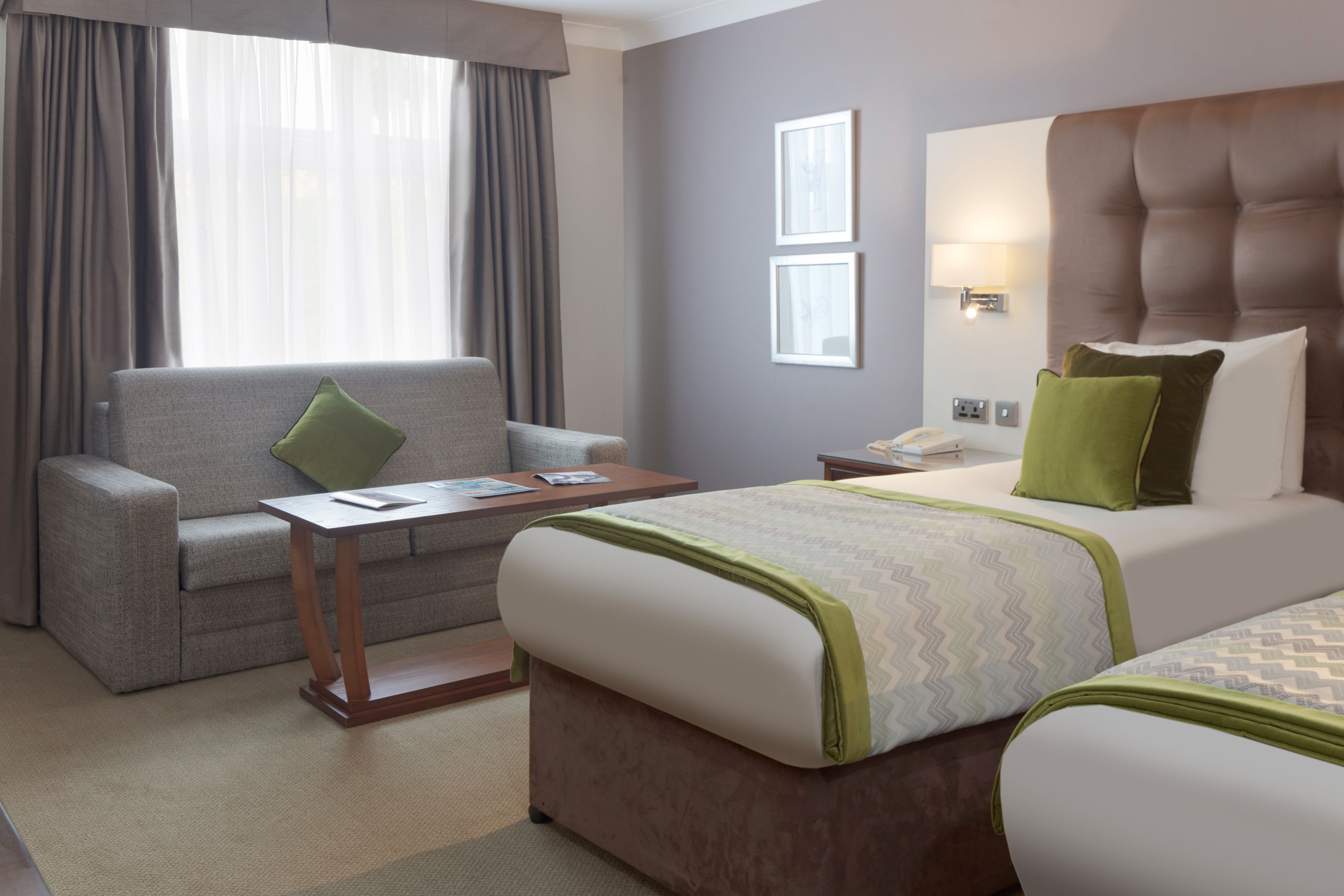Ein Hotelzimmer mit einem Bett, einer Couch, einem Nachttisch und einer Lampe.