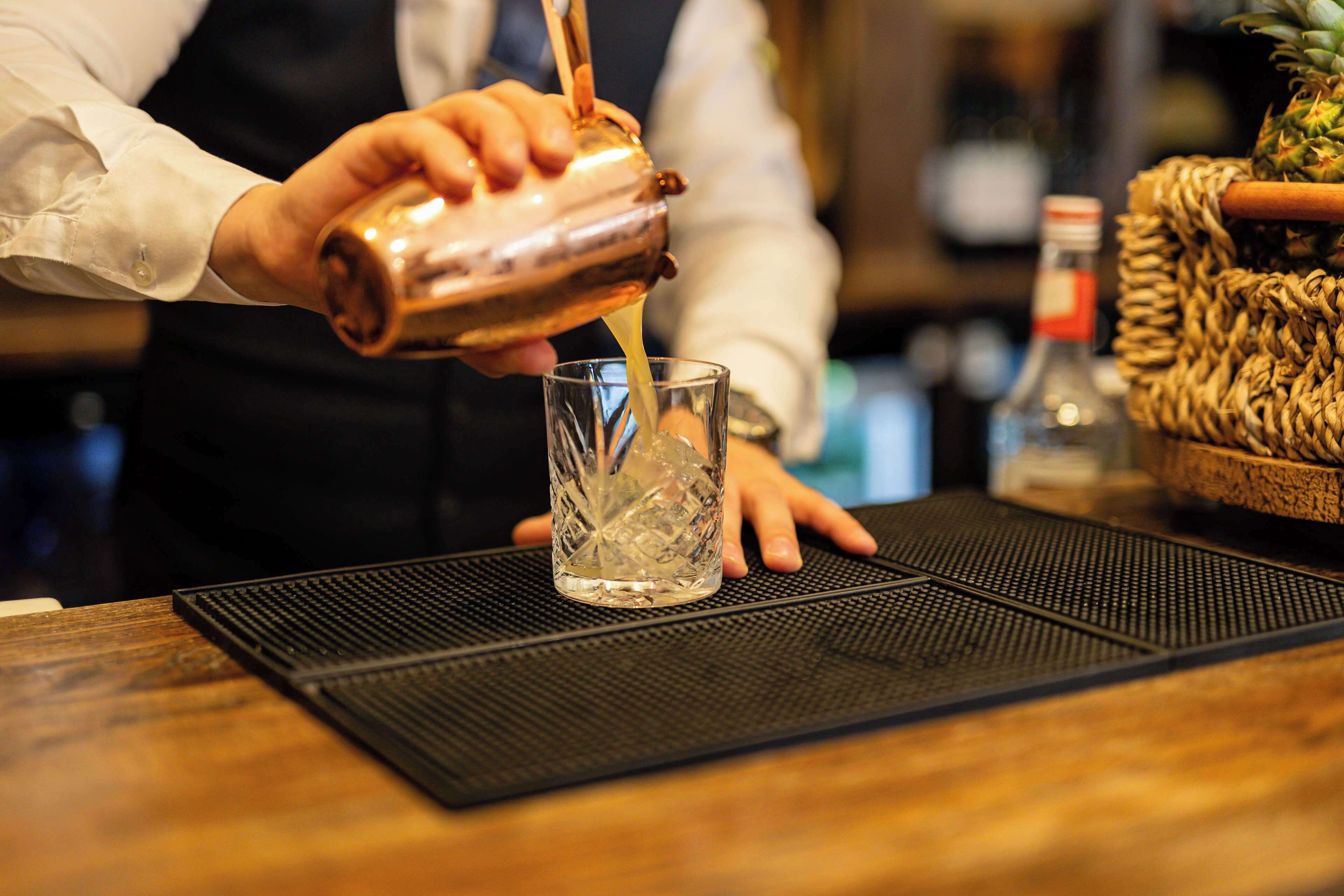 A bartender pouring a drink into a glass.