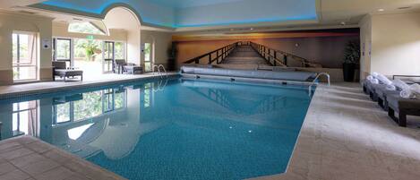 An indoor swimming pool with a clear view of the stairs leading to the upper level.