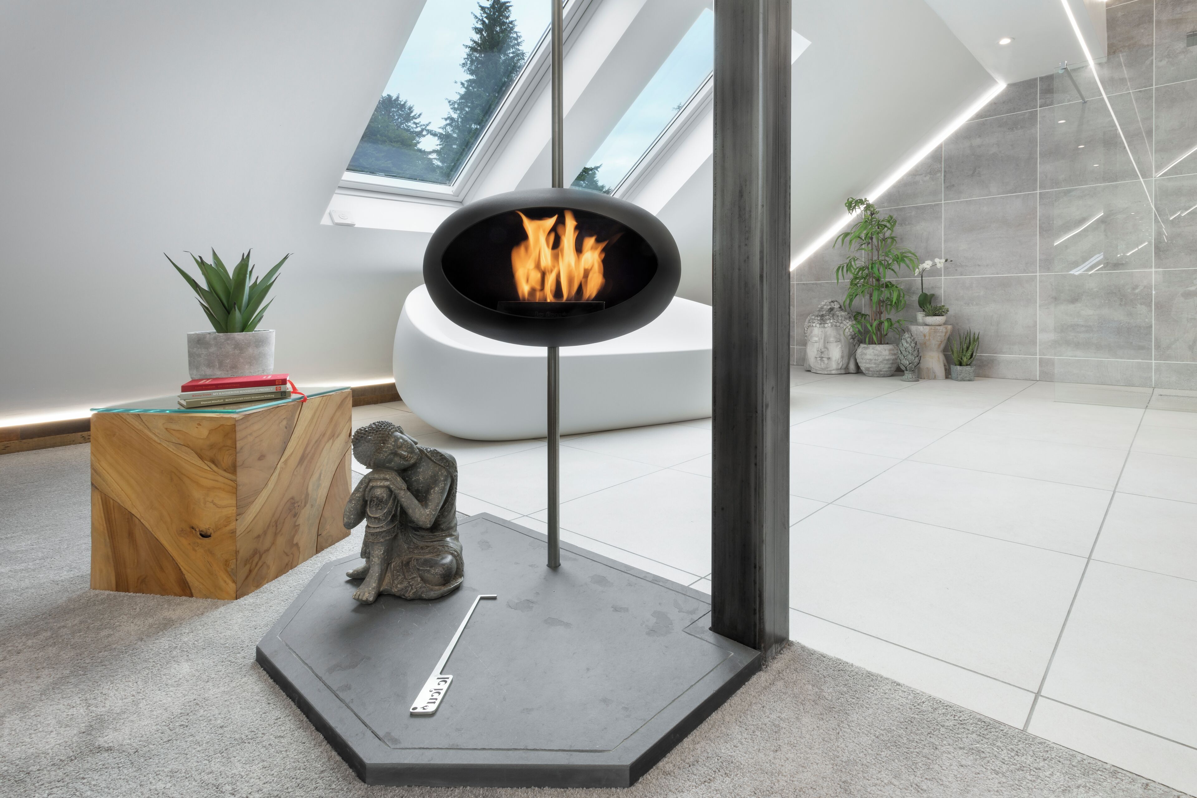 Ein modernes Interieur mit zentralem Kamin, einem Holztisch mit Pflanze und einer Skulptur auf einer Plattform.
