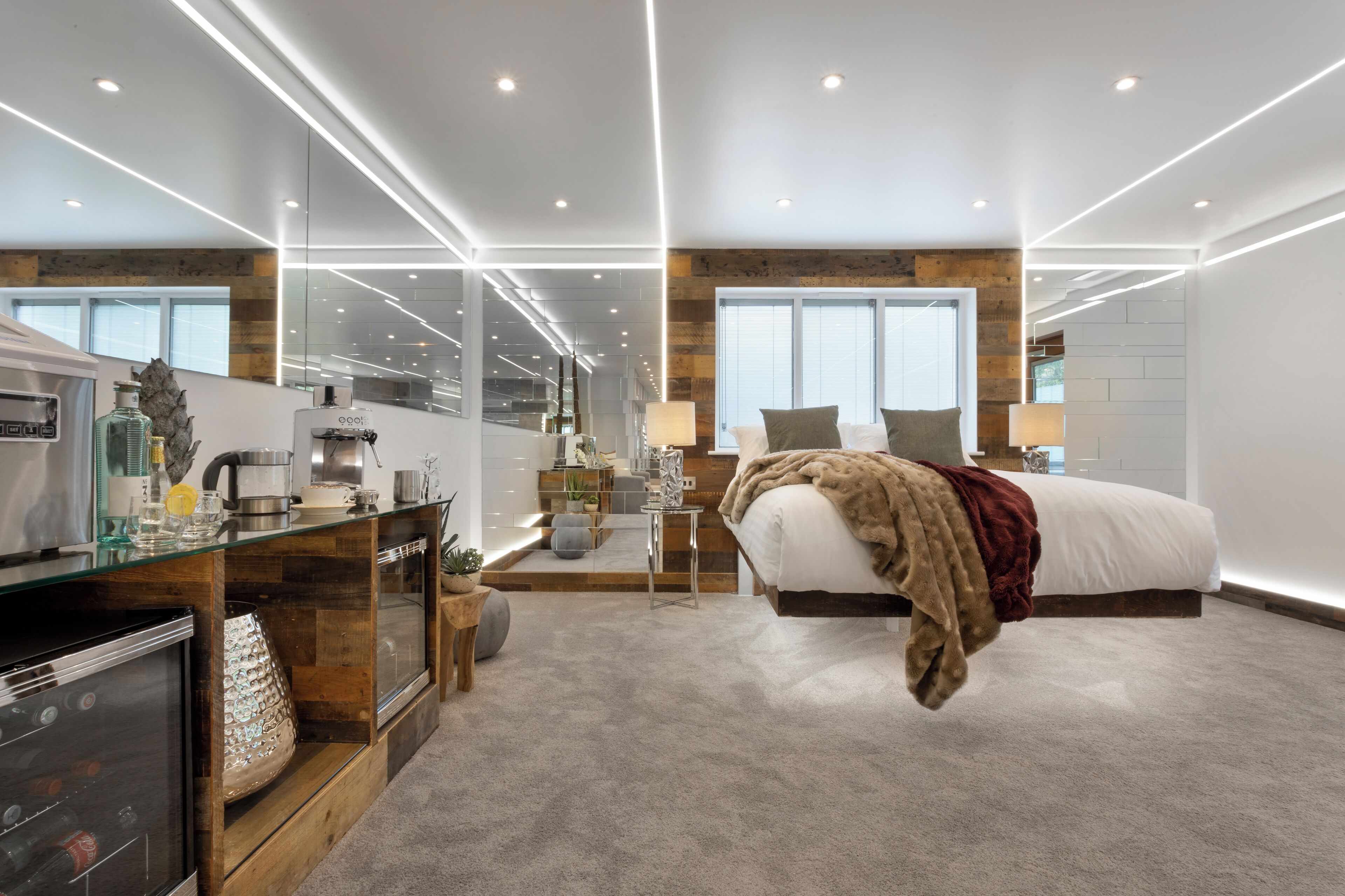 A modern bedroom with a large bed, a glass coffee table, and a built-in refrigerator.
