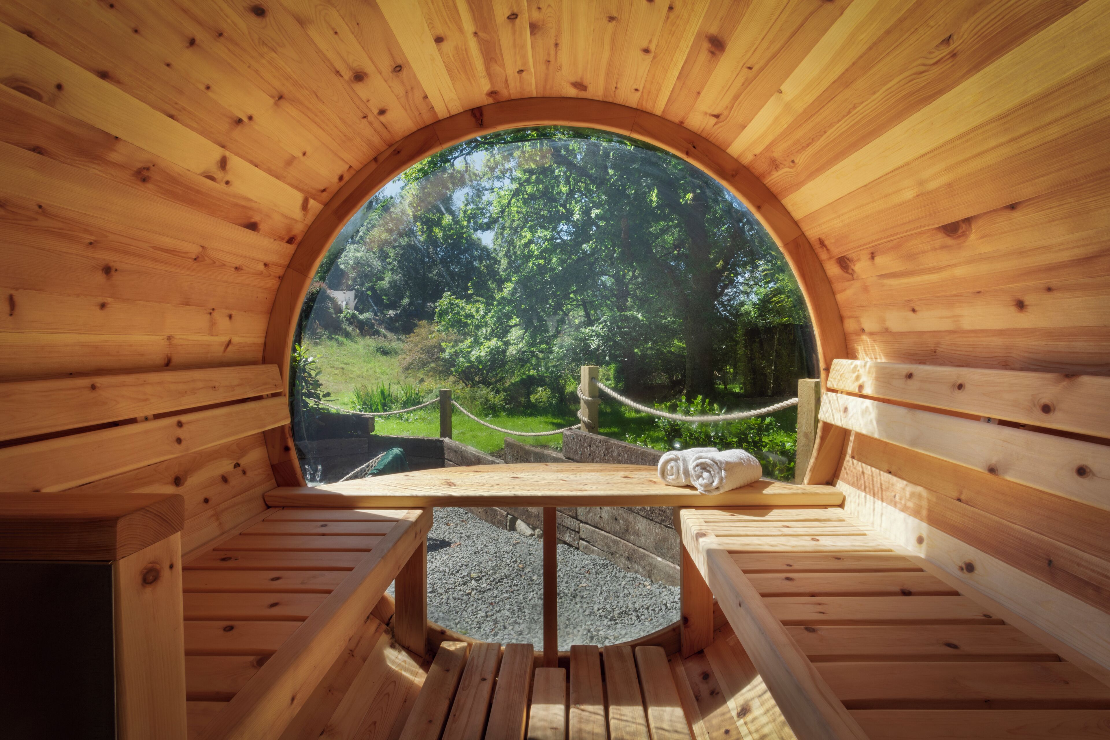 A wooden sauna with benches and a circular window.