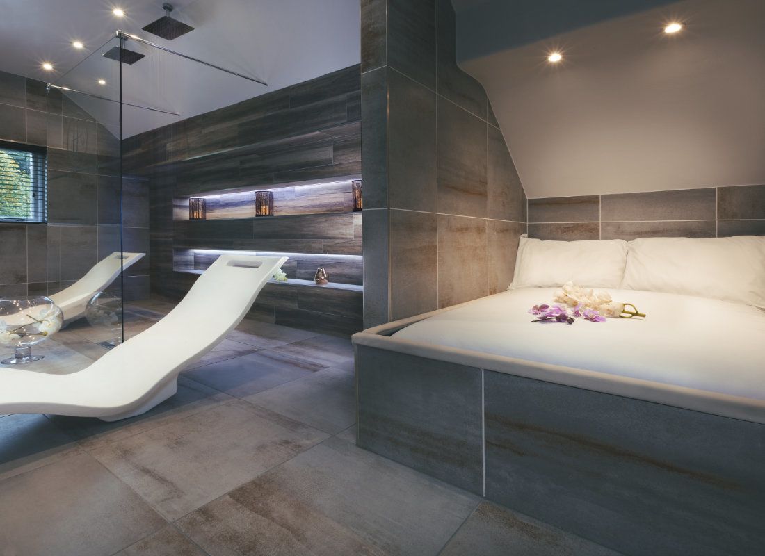 A modern bedroom with a curved bed, a glass shower enclosure, and a built-in bench with shelves.