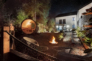 A cozy outdoor area with a fire pit, wooden seating, and a large wooden structure. - Aphrodites Group (Windermere)