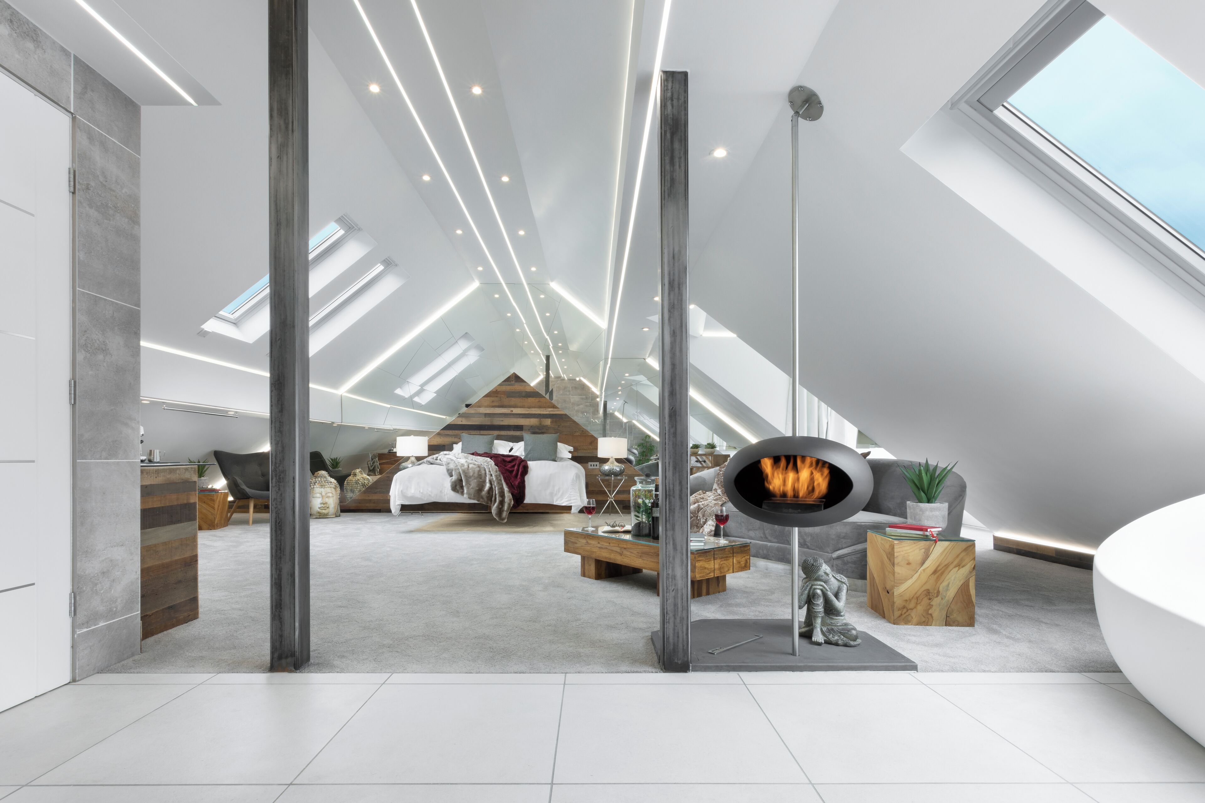 Un dormitorio tipo loft moderno con tragaluces, chimenea y un rincón de estar acogedor.