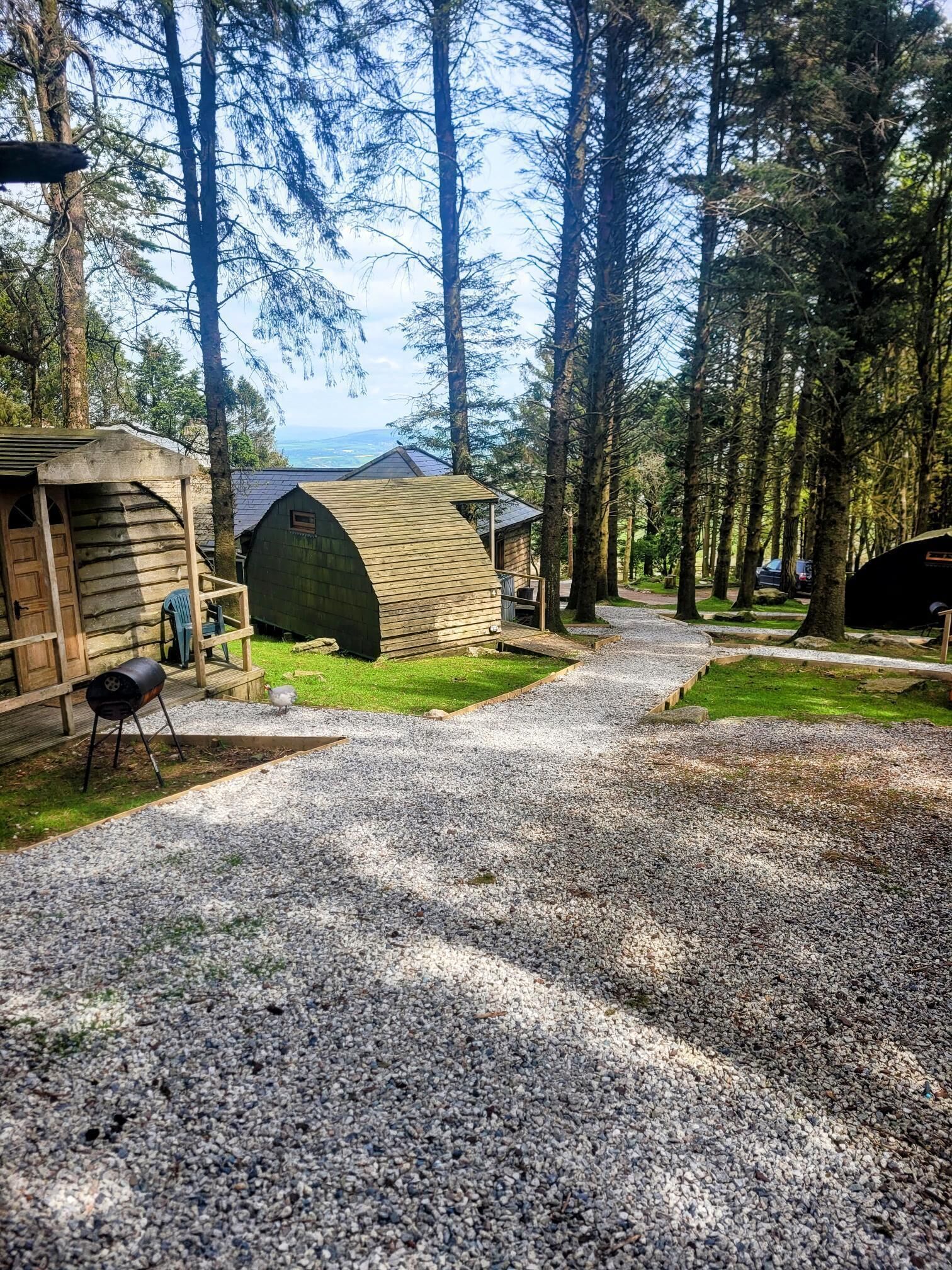 Un camping con cabañas de madera, senderos de grava y una zona de césped.