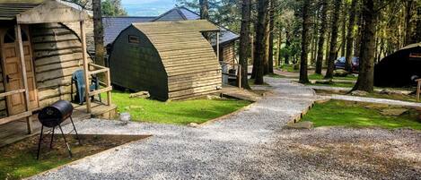 Un camping con cabañas de madera, senderos de grava y una zona de césped.
