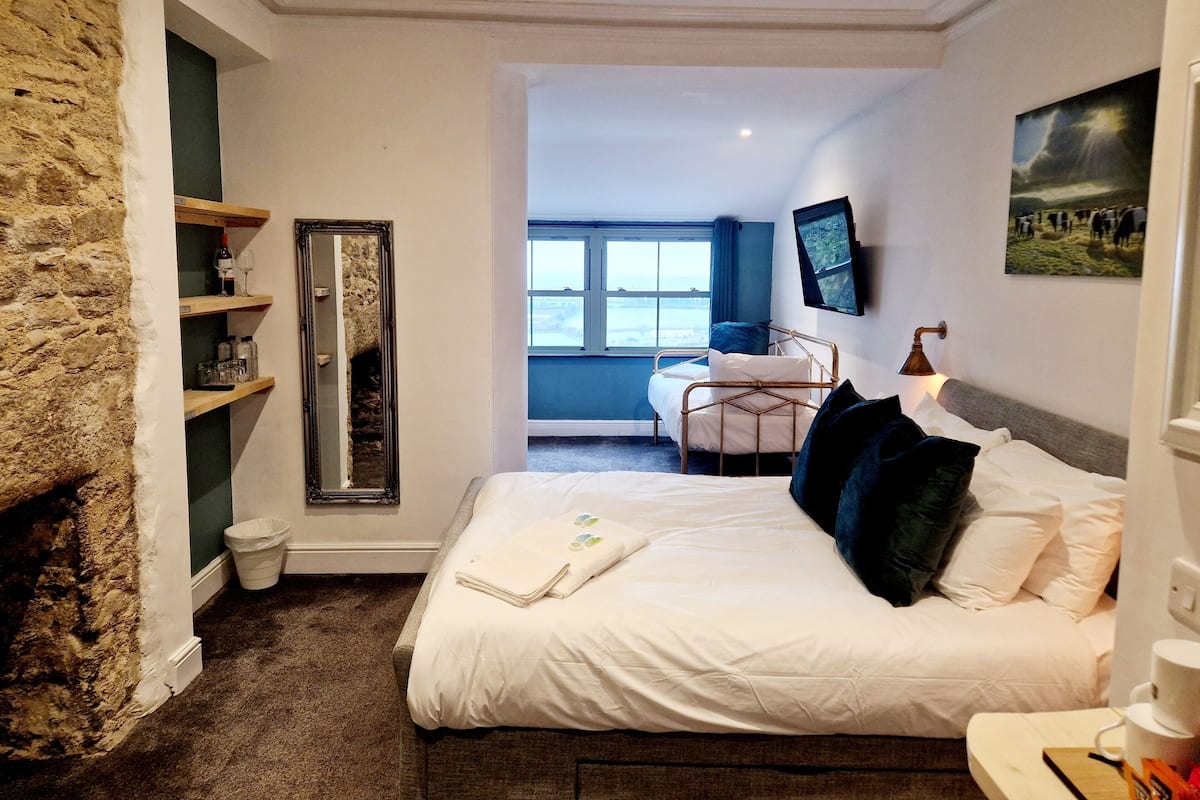 Una camera da letto con un letto, uno specchio, scaffali, una televisione e una finestra.