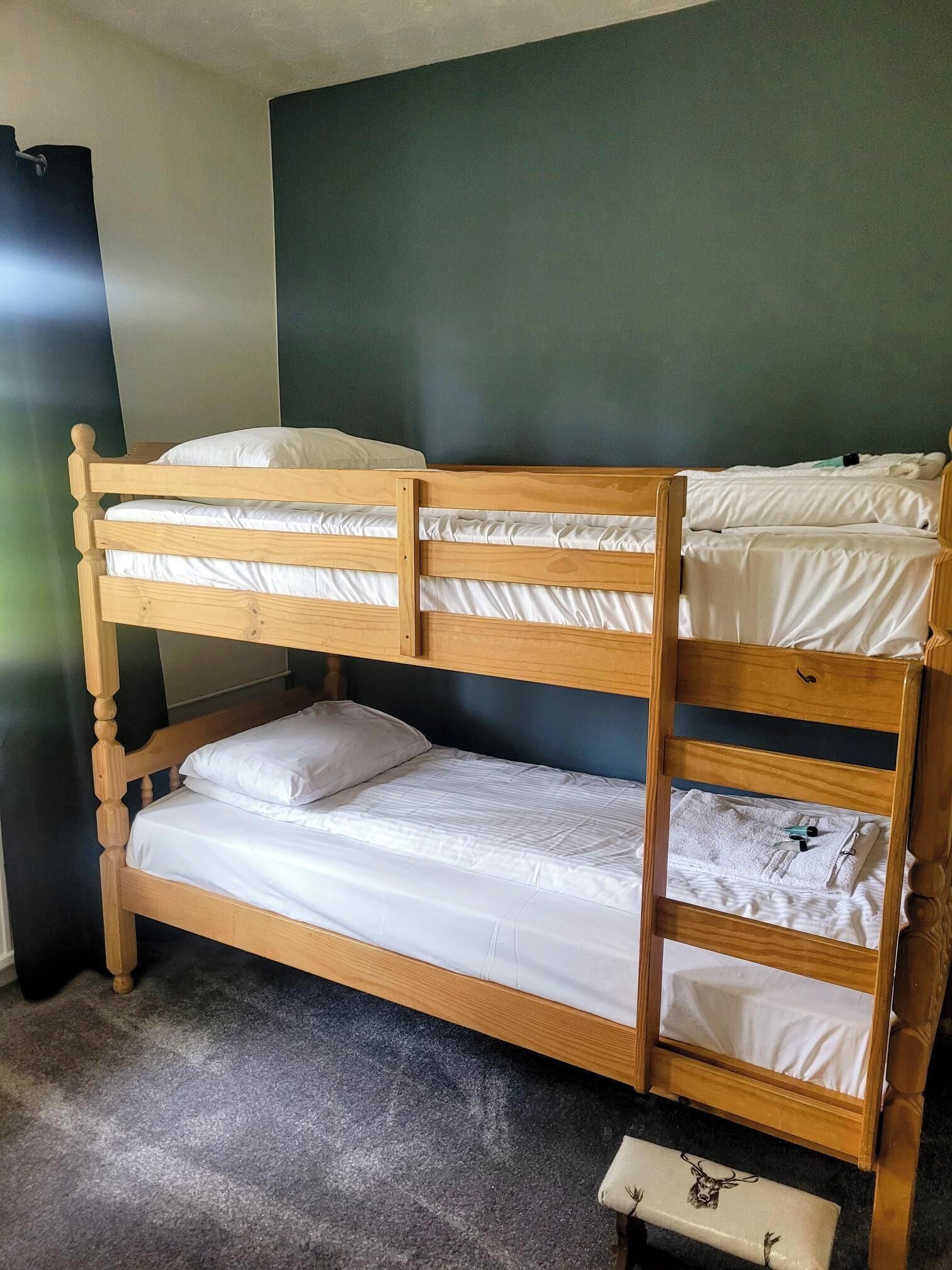Una cama literera de tres niveles, una mesita de noche pequeña y una pared lisa.