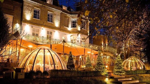 Un hotel con una estructura de cúpula de vidrio, un balcón con barandillas y árboles de Navidad.