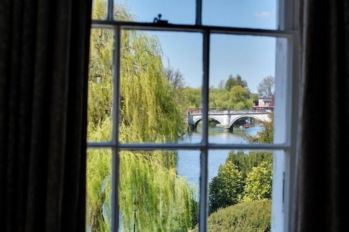 A view through a window with a view of a bridge over a river, surrounded by greenery.