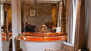 Un baño con una bañera grande, un espejo y una silla de madera.