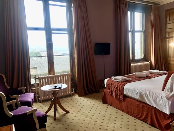 A hotel room with a bed, a chair, a table, and a TV. - Purbeck House Hotel (Swanage)