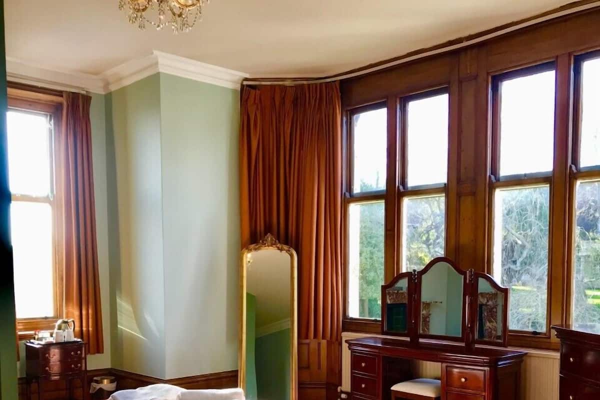 A hotel room with a large bed, a dresser, a mirror, and a telephone.
