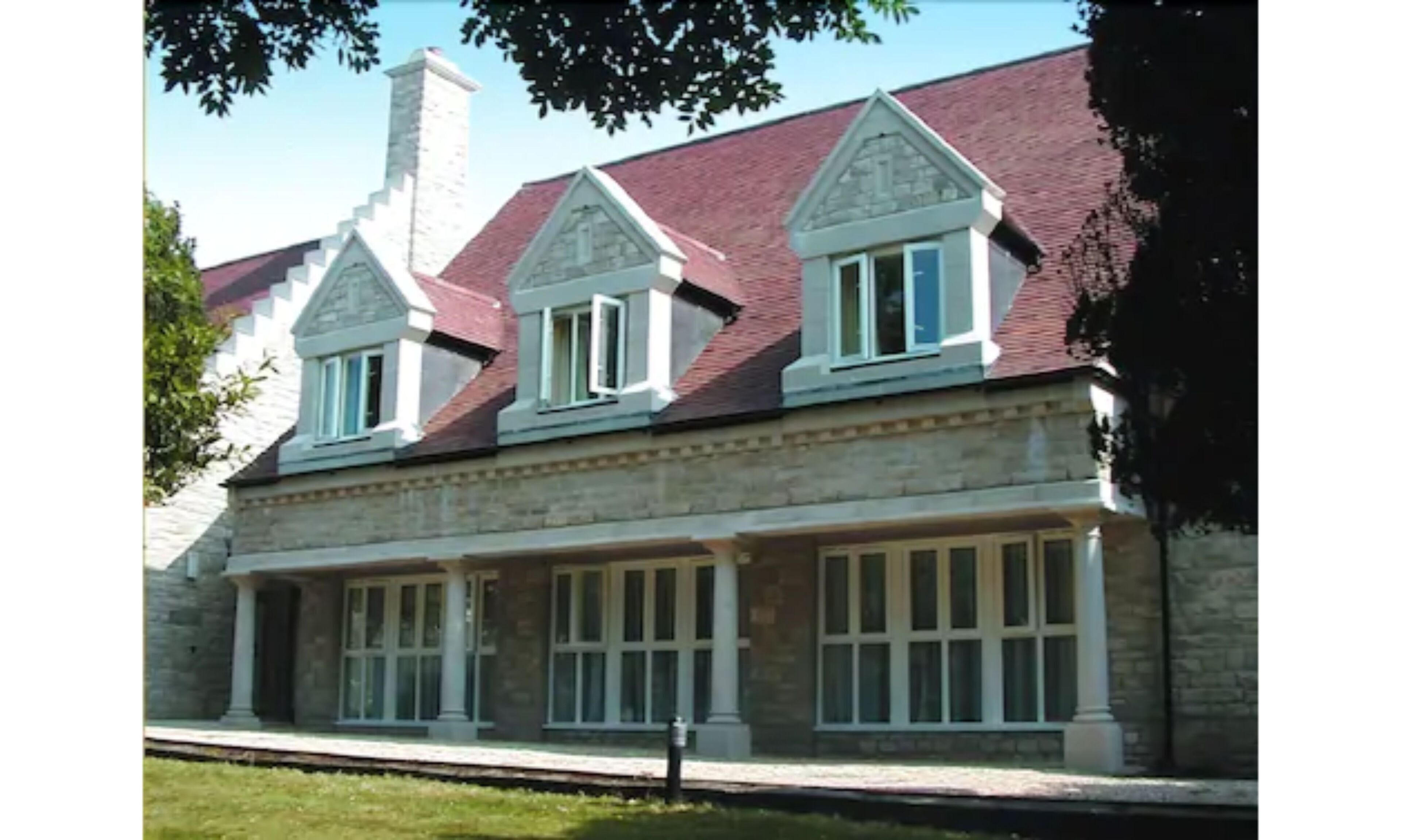 Un bâtiment en pierre avec un toit rouge et de nombreuses fenêtres.