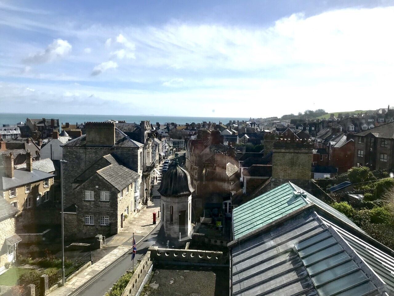 A coastal town with historic stone buildings, a prominent church, and a view of the sea.