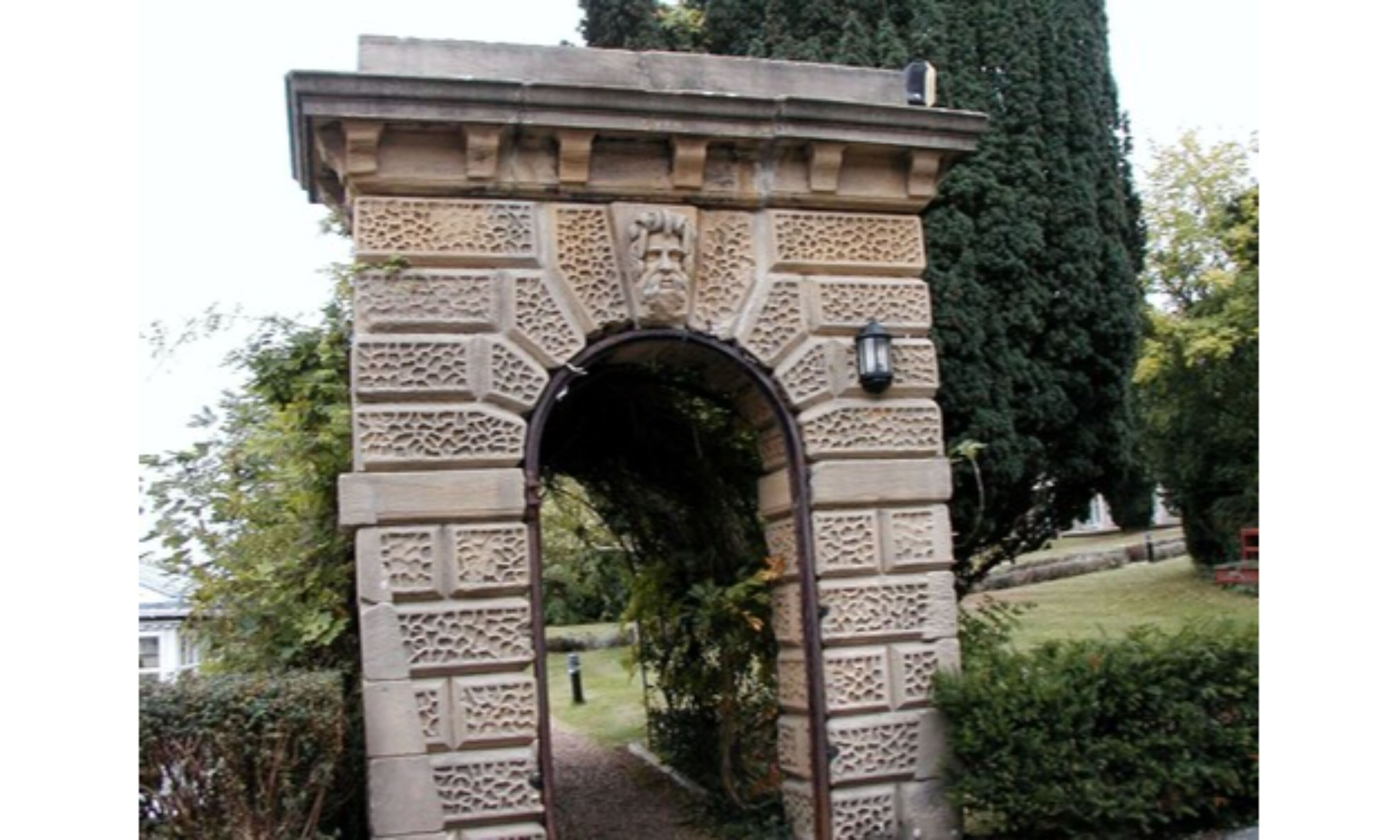 A stone archway with intricate carvings and a lantern on top.