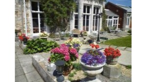 A building with large windows and a garden with various flowers. - Purbeck House Hotel (Swanage)