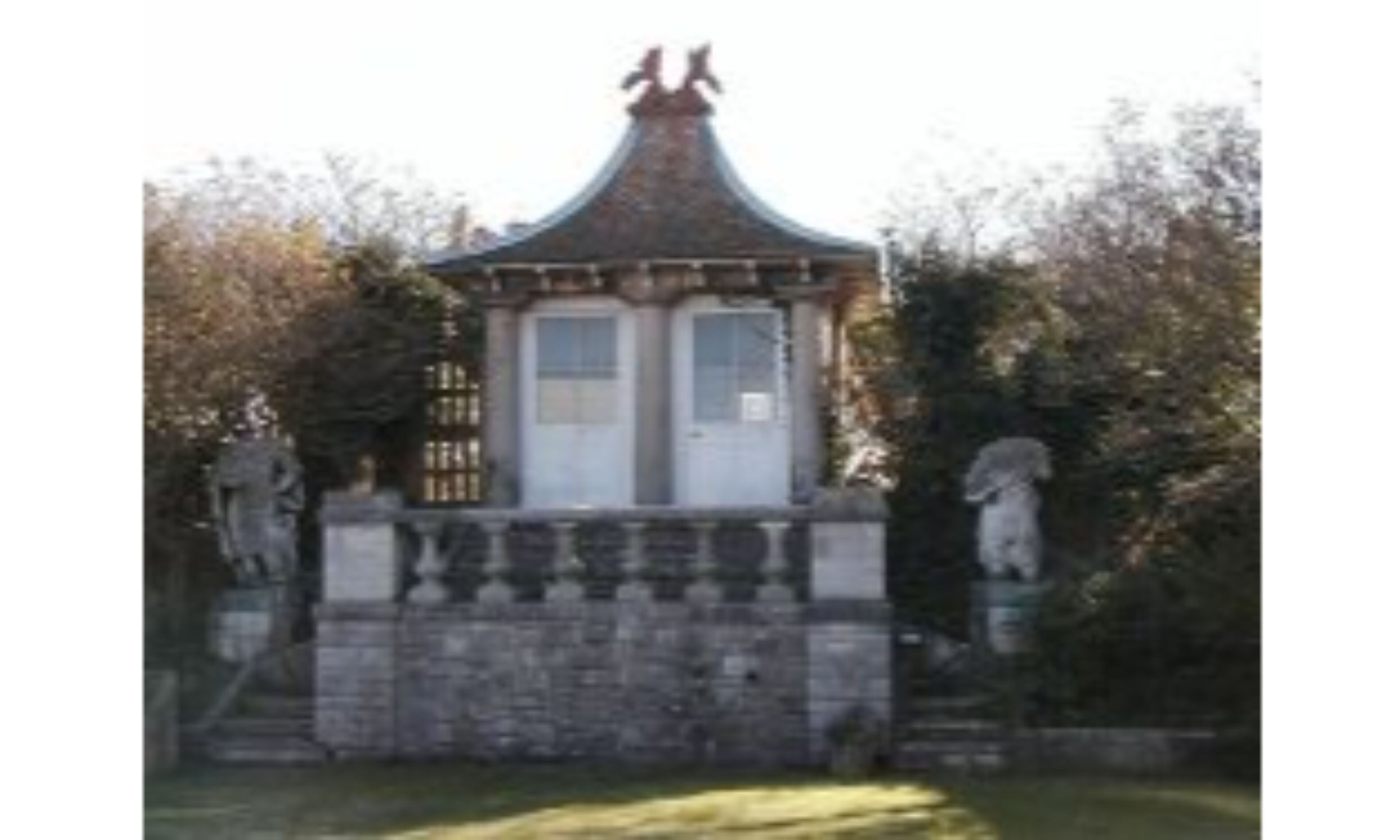 Un bâtiment traditionnel avec un toit en tuiles, une base en pierre et deux statues de chaque côté.