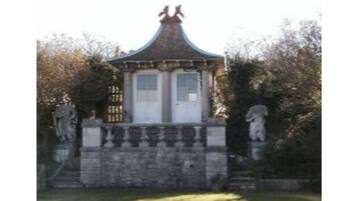 Un bâtiment traditionnel avec un toit en tuiles, une base en pierre et deux statues de chaque côté.