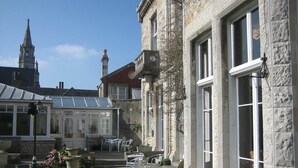A courtyard with stone buildings, a conservatory, and outdoor seating. - Purbeck House Hotel (Swanage)