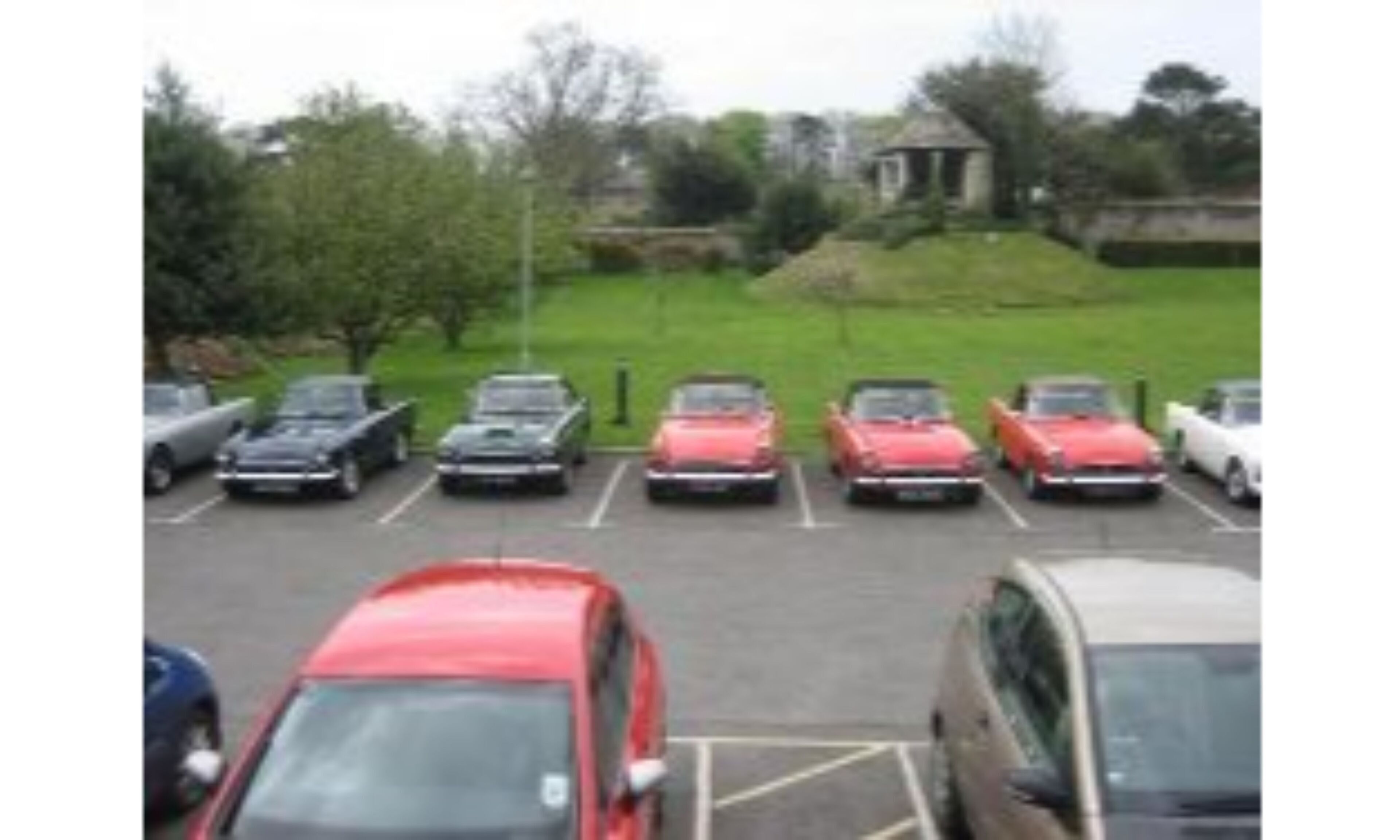 A parking lot with several cars parked in rows.