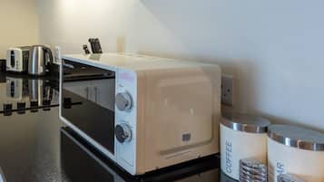 Een kitchenette met een koffiezetapparaat, een broodrooster en twee bakken met daarop 'Koffie' en 'Lucht'.