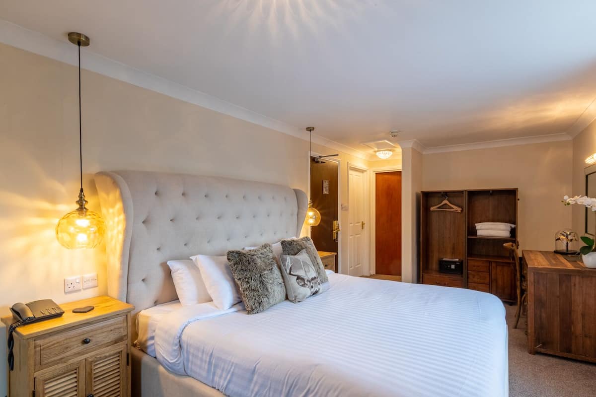 A neatly arranged bedroom with a large bed, bedside tables, a wardrobe, and a hanging wardrobe.