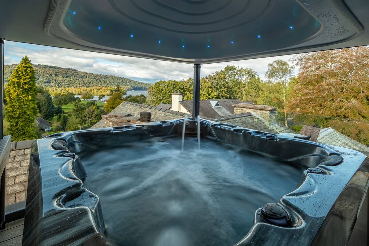 A hot tub with a panoramic view of a lake and forested hills.