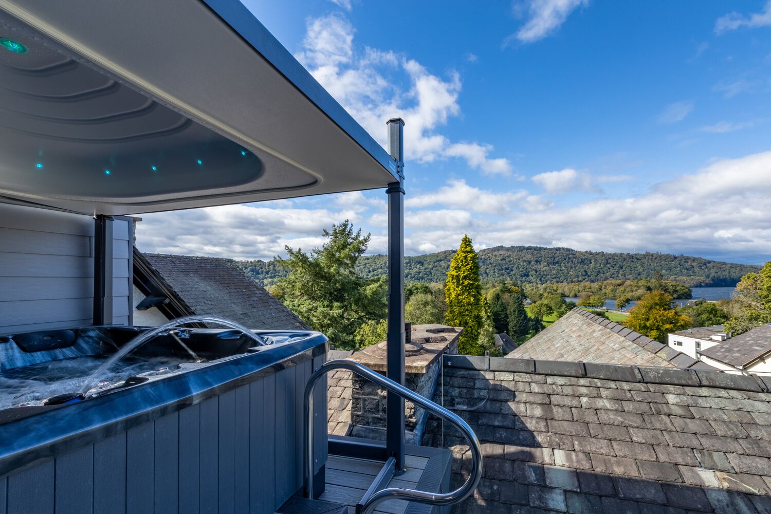 A hot tub on a rooftop with a view of a lake and hills.