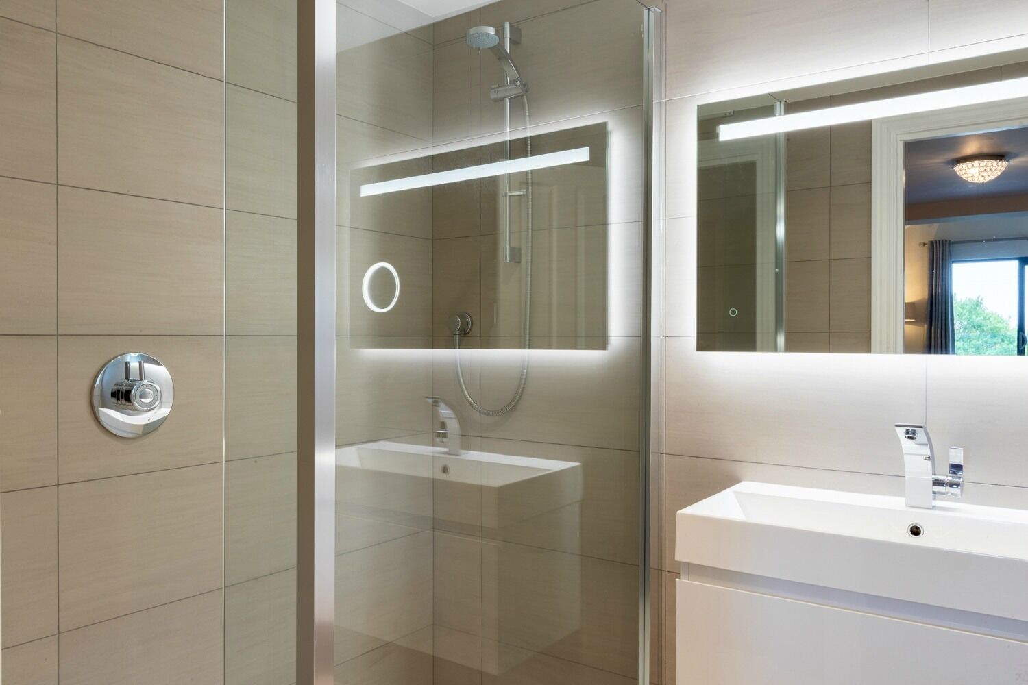 A modern bathroom with a glass-enclosed shower, a white sink, and a large mirror.