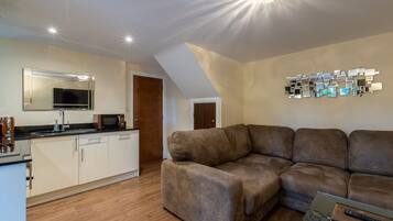 A modern living room with a brown sectional sofa, a glass coffee table, and a flat-screen TV.
