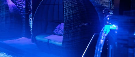 A room with a hanging chair and a small pool area.