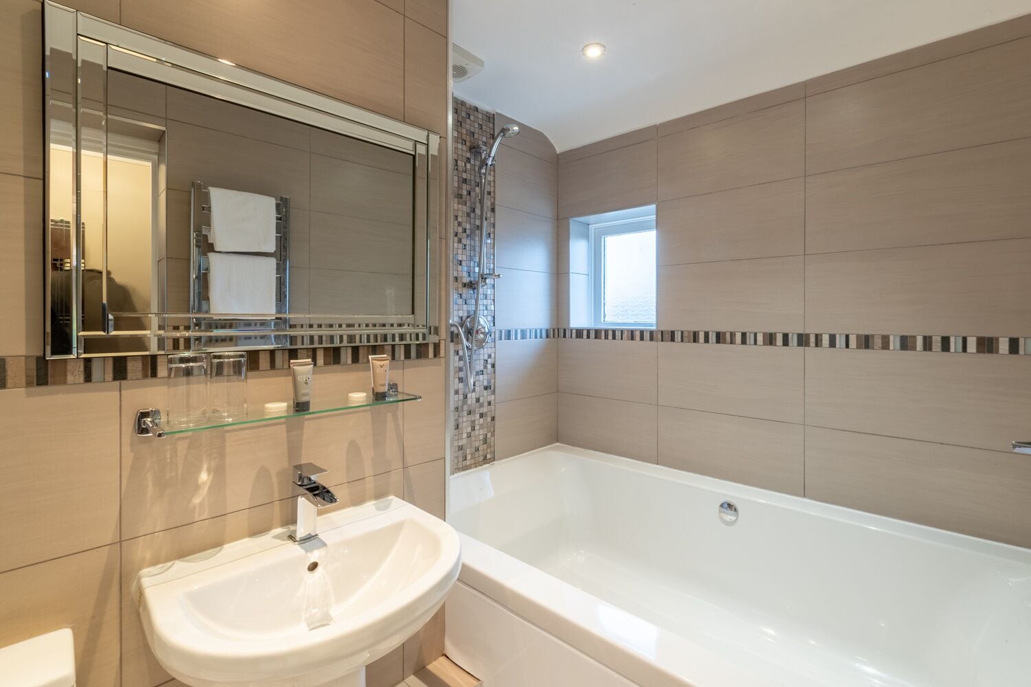 A modern bathroom with a large bathtub, a glass-enclosed shower, and a white sink.