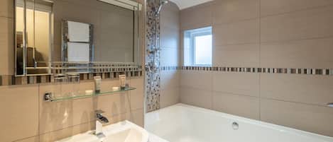 Une salle de bain moderne avec une grande baignoire, une douche à l’italienne et un lavabo blanc.