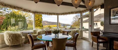 A dining area with a round glass table, leather chairs, and a view of the outdoors.