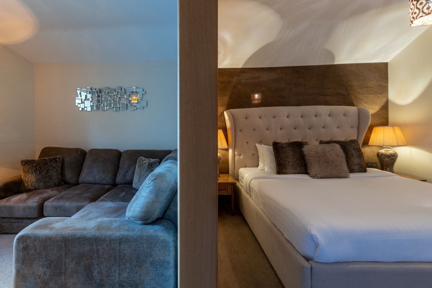 A modern hotel room with a sofa, a bed, and a decorative wall piece.