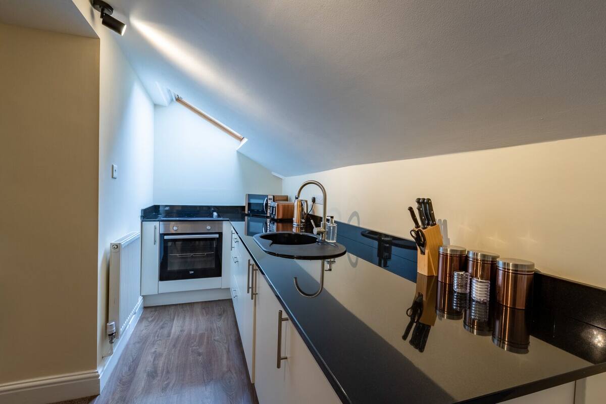A compact kitchen with a built-in oven, a sink, and a coffee machine.
