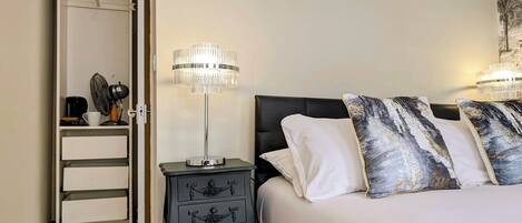 A bedroom with a bed, two bedside lamps, a nightstand, a closet, and a wall-mounted artwork.