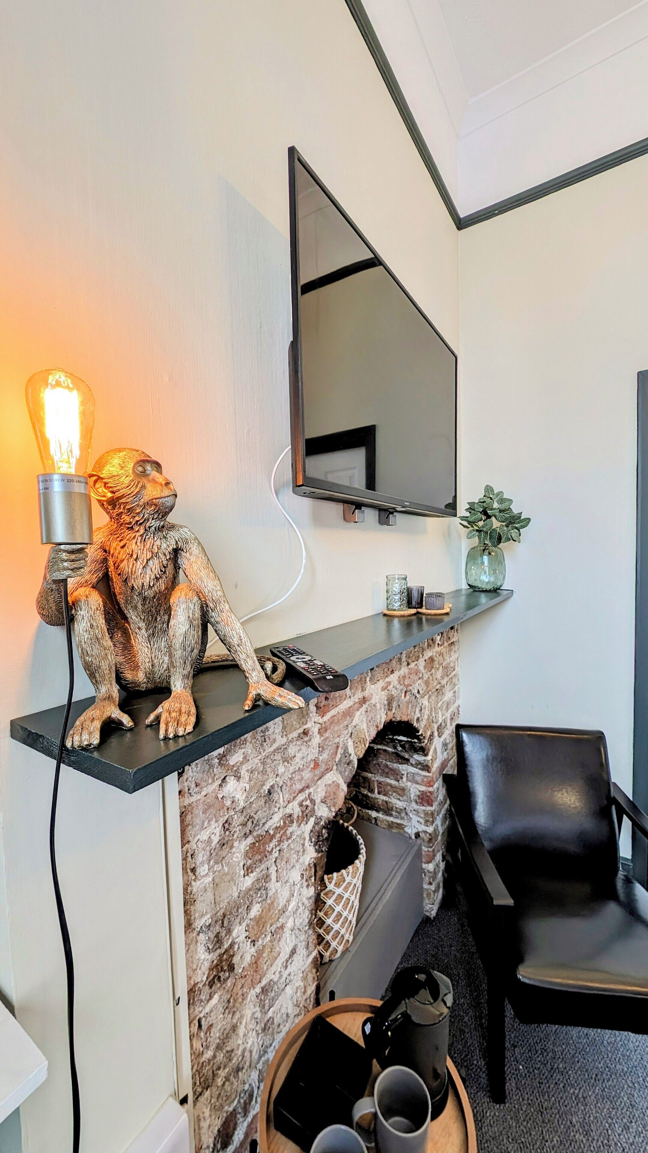 A modern living room with a brick fireplace, a mounted TV, and a decorative monkey sculpture.